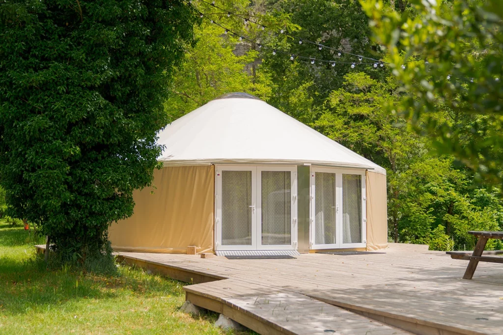 Une yourte premium dans un espaces vert entouré d'une terrasse bois.